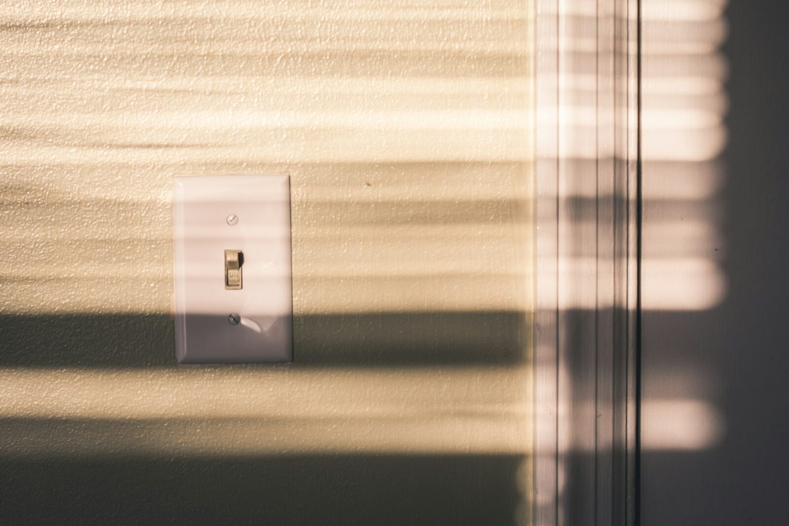 Vypínač na zdi v pruhu slunečního světla