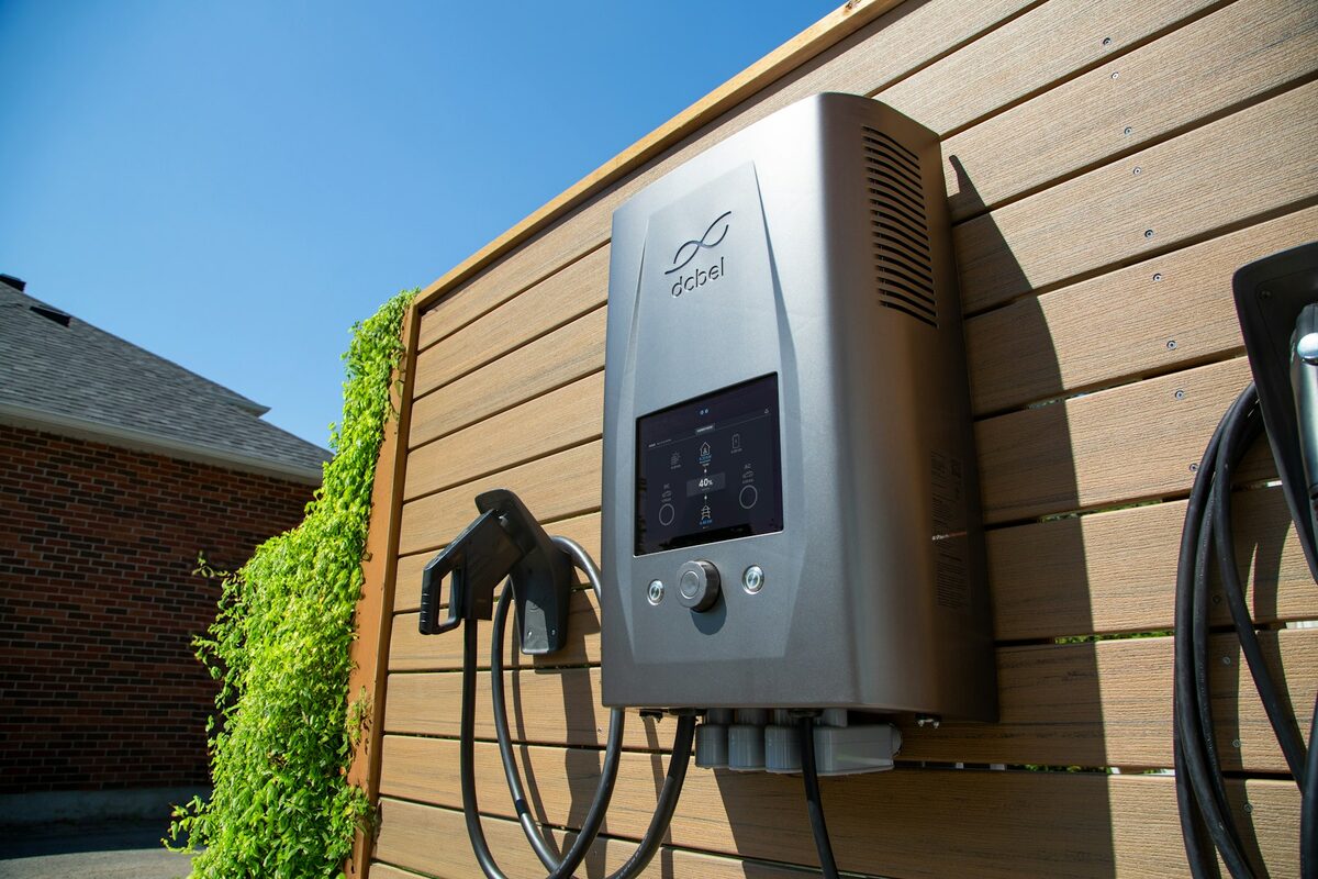 Nabíječka elektroauta na dřevěné stěně u domu